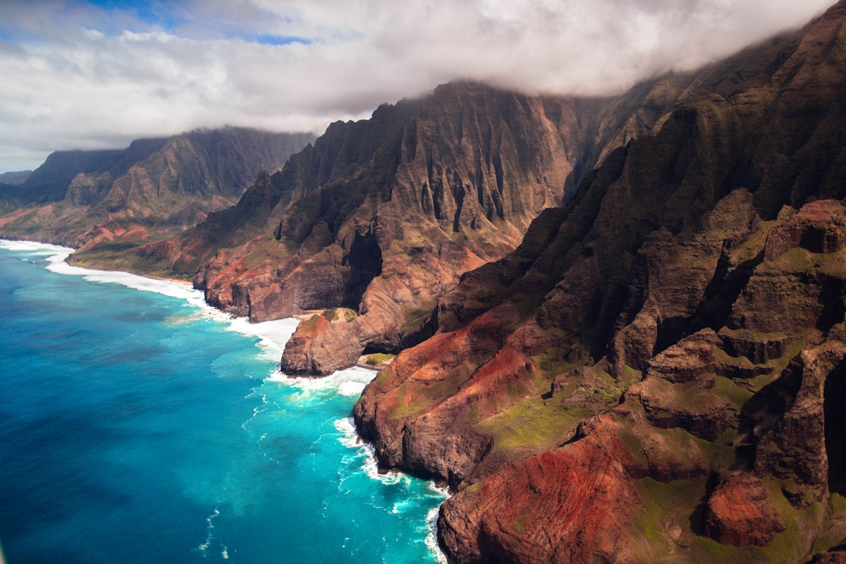 An aerial view of Hawaii's lush volcanic sea cliffs above turquoise surf